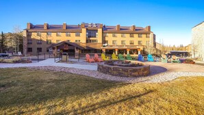 A multi-story building with a patio area featuring outdoor seating and a fire pit. - Cozy Brian Head Condo: Walk to Navajo Express Lift (Brian Head)