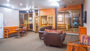 A cozy living area with a sofa, chairs, and a coffee table. There is a sliding glass door leading to a kitchen area. - Cozy Brian Head Condo: Walk to Navajo Express Lift (Brian Head)