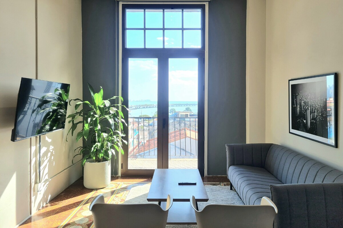 A modern living room with a large window, a flat-screen TV, a sofa, a coffee table, and a potted plant.