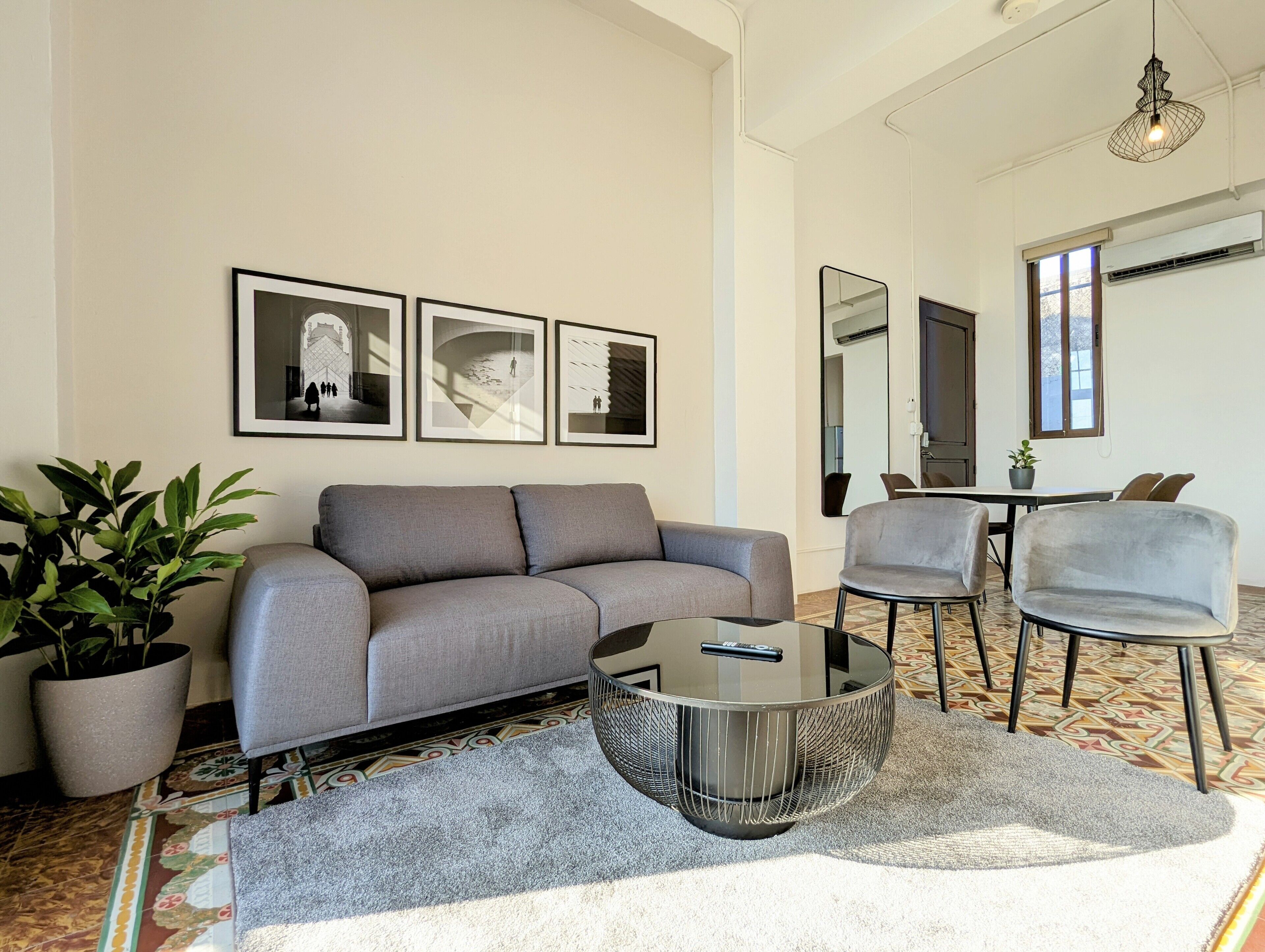 Ein modernes Wohnzimmer mit einem grauen Sofa, einem Glastisch und einer Topfpflanze.