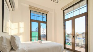 A bedroom with a bed, a window, and a view of buildings. - Donovan Night Scene by Wynwood (Panama City)