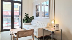 A room with a white sofa, a wooden chair, a small table, a potted plant, and framed pictures on the wall. - Donovan Night Scene by Wynwood (Panama City)