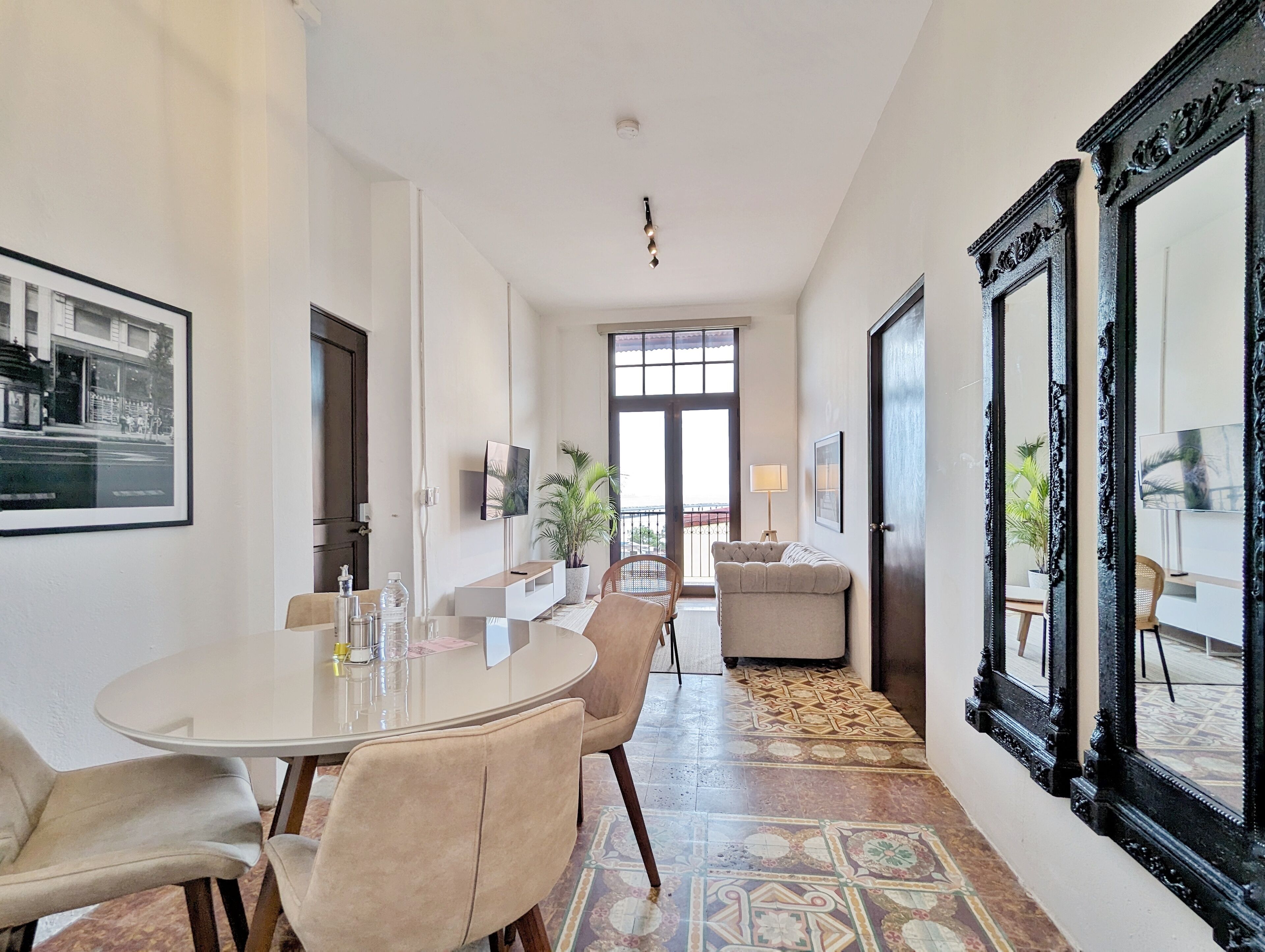Un coin repas avec une table ronde, des chaises, une plante en pot et un grand miroir.