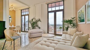 A spacious living room with a large sofa, a round coffee table, and a dining area with chairs and a table. There are large windows offering a view of the cityscape. - Donovan Night Scene by Wynwood (Panama City)