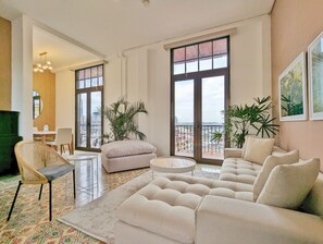 A spacious living room with a large sofa, a round coffee table, and a dining area with chairs and a table. There are large windows offering a view of the cityscape. - Donovan Night Scene by Wynwood (Panama City)