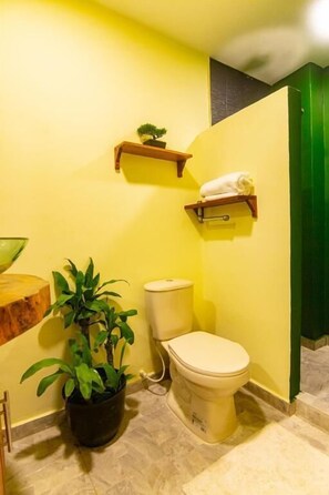 A small bathroom with a toilet, a sink, and a potted plant. - Waikiki Beach Hostel (Dibulla)