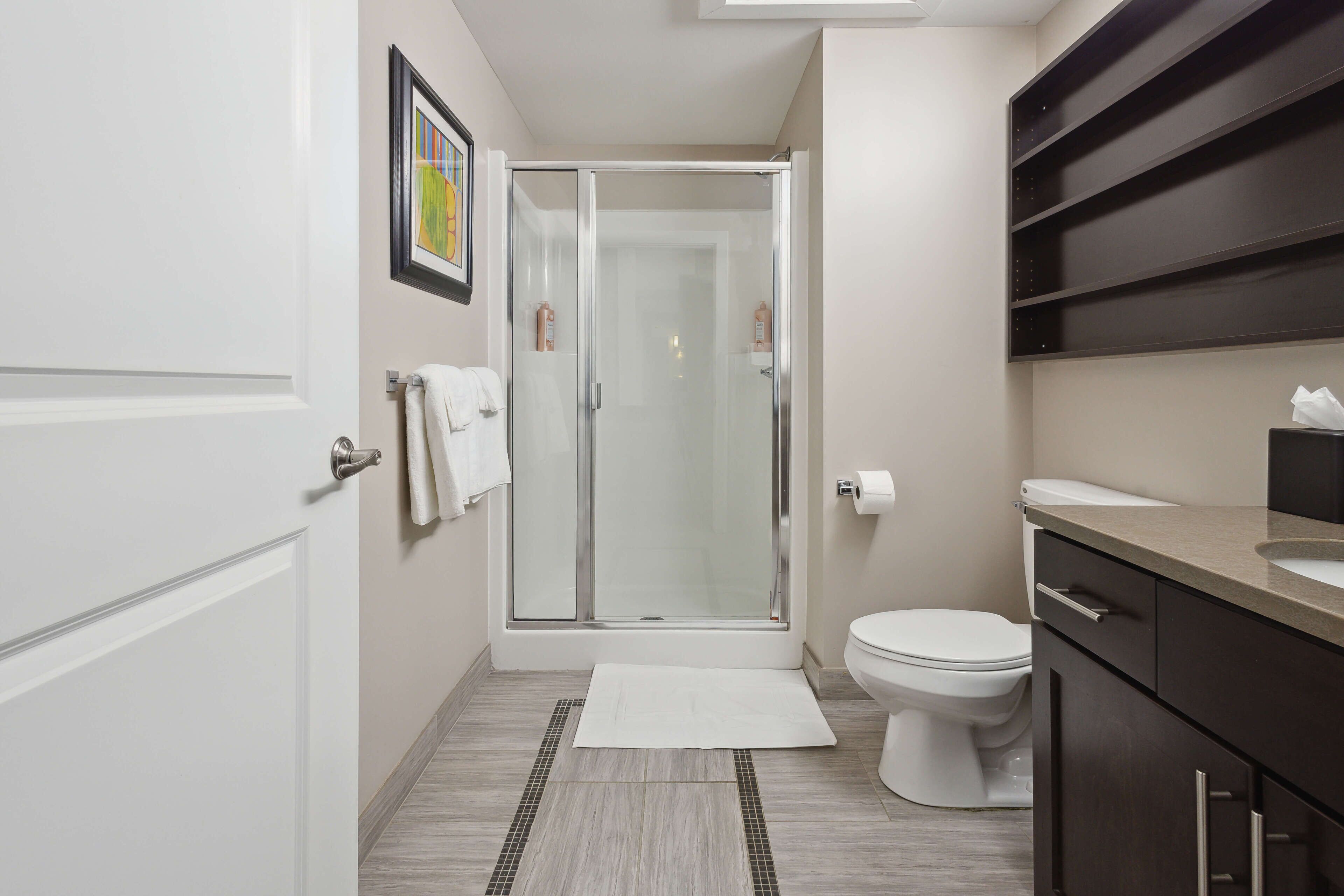 A modern bathroom with a glass shower enclosure, a toilet, and a vanity with a sink.