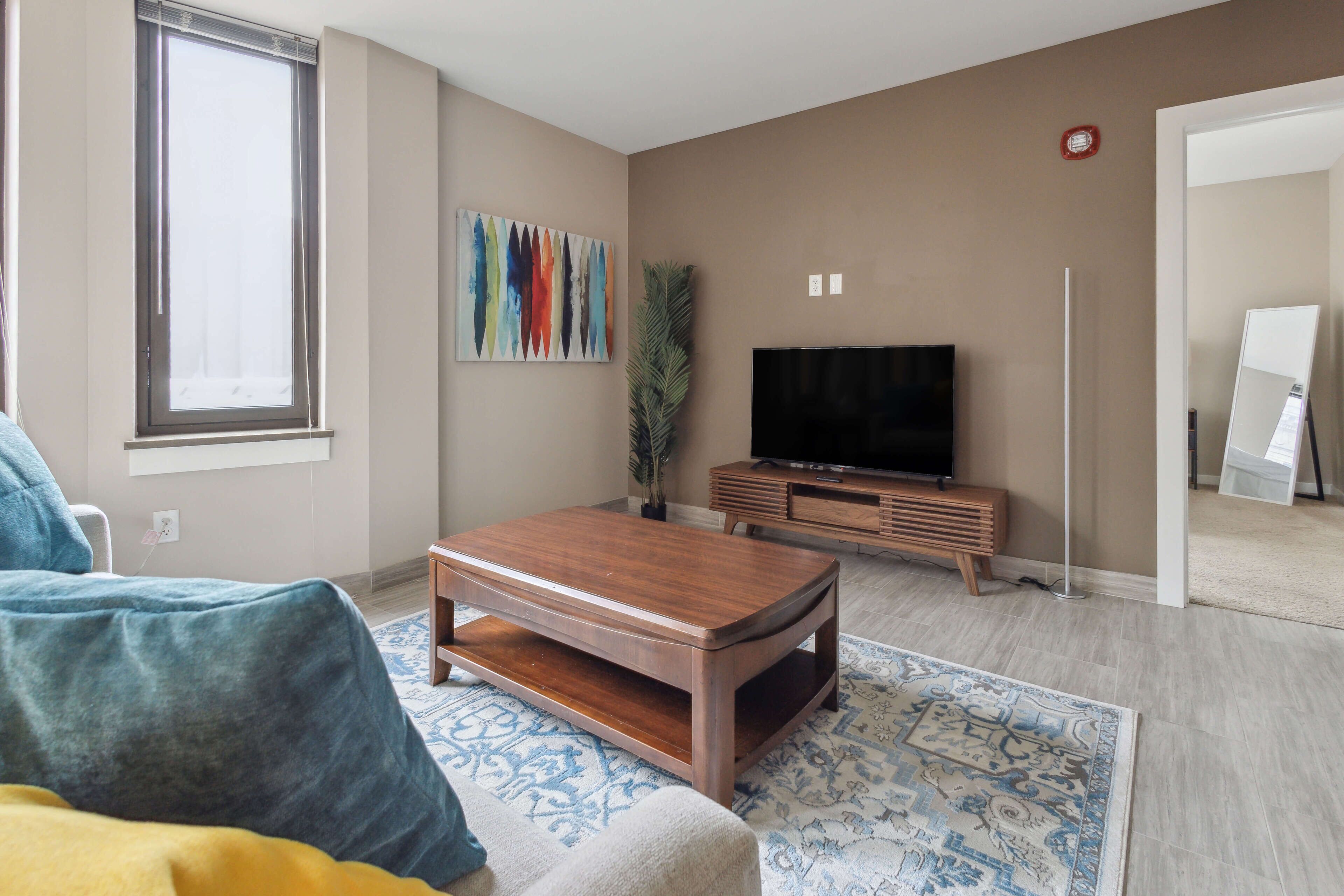 A living room with a wooden coffee table, a television, and a patterned rug.