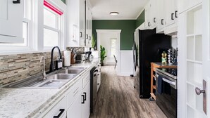 Une cuisine moderne avec des meubles blancs, un plan de travail en granit et un réfrigérateur noir.