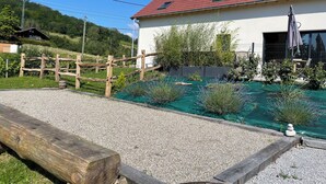 A house with a red roof, a gravel driveway, and a wooden fence. - Gîte des 5 Cépages Avec Jacuzzi (L'Étoile)