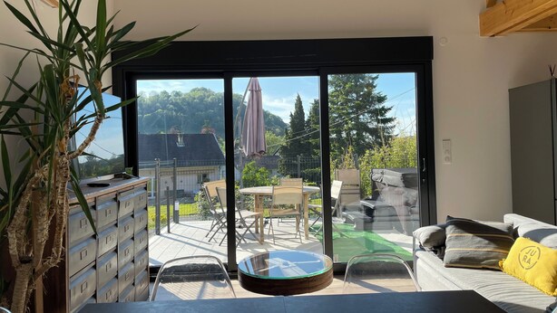 A modern room with a sliding glass door leading to an outdoor patio area. - Gîte des 5 Cépages Avec Jacuzzi (L'Étoile)