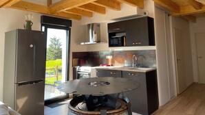 A modern kitchen with wooden beams, a stainless steel refrigerator, a microwave, and a stove. - Gîte des 5 Cépages Avec Jacuzzi (L'Étoile)
