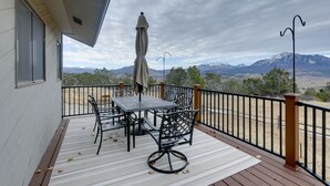 Een balkon met een tafel, stoelen, een parasol en uitzicht op bergen.