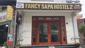 Un edificio con un letrero que dice "FANCY SAPA HOSTEL 2" y el número "26" en la puerta.