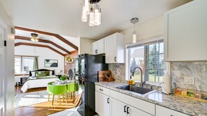Una cocina moderna con armarios blancos, un refrigerador negro y una encimera de granito.