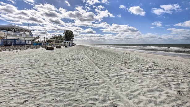 Ein Sandstrand mit einem Gebäude und einem Baum im Hintergrund.