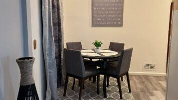 Un coin repas avec une table et des chaises, un vase décoratif et une citation inspirante sur le mur.