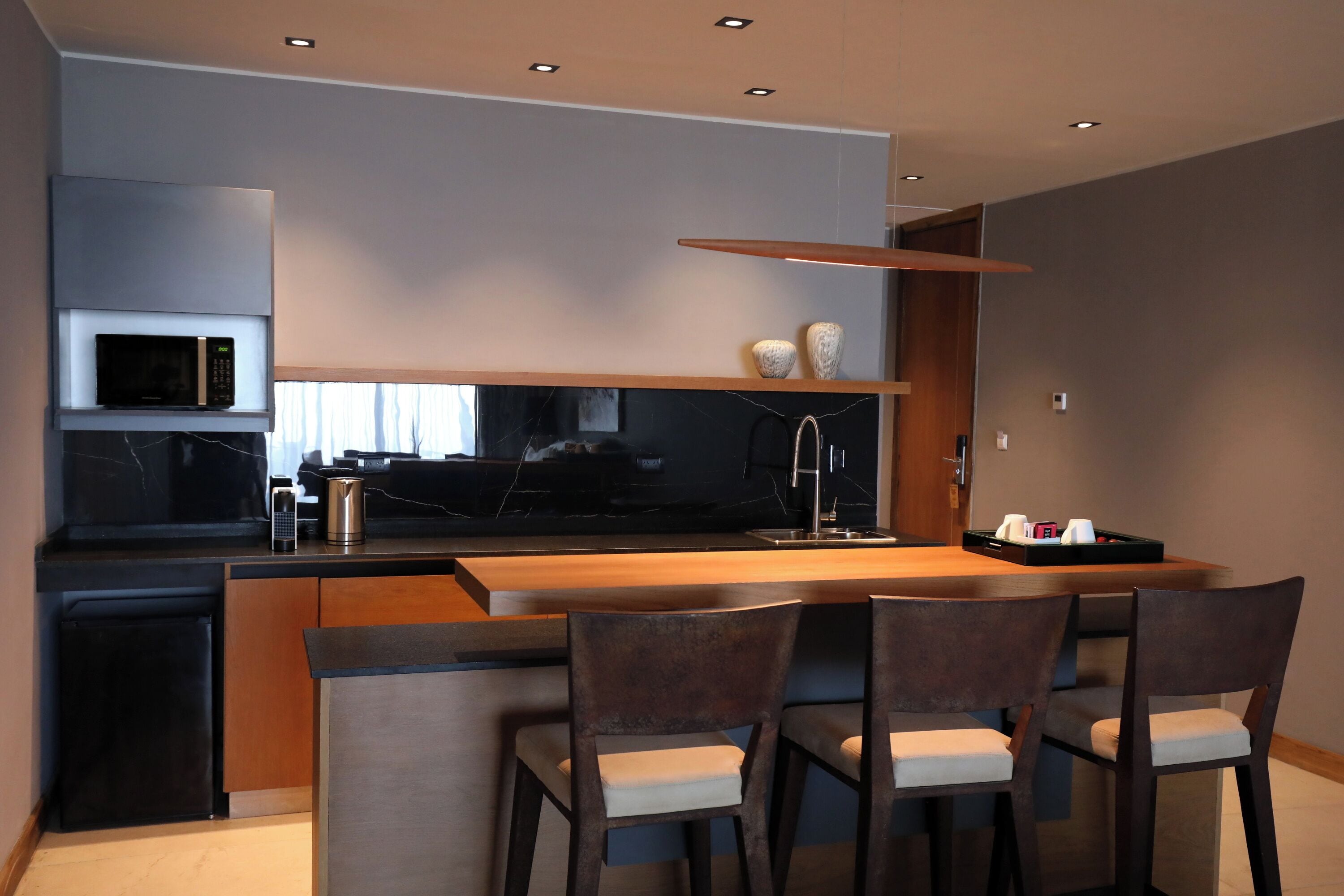 A modern kitchen with a central island, four chairs, and a built-in microwave.