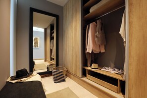 A bedroom with a bed, a wooden wardrobe, a mirror, and a small table with slippers and a hat. - Puesto del Indio (Mendoza)