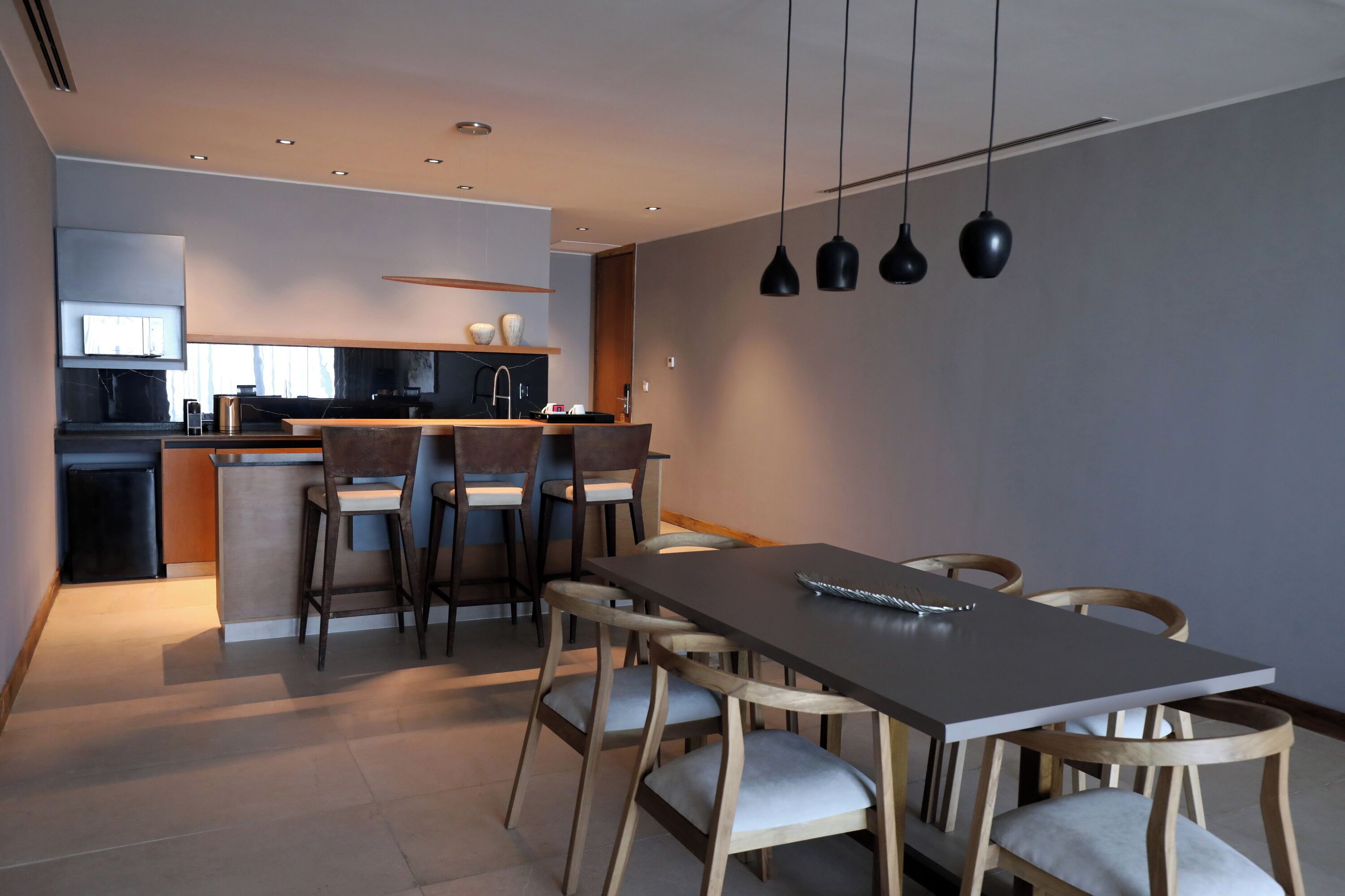 Una cocina moderna con comedor, que incluye una mesa larga y sillas, e iluminación colgante.