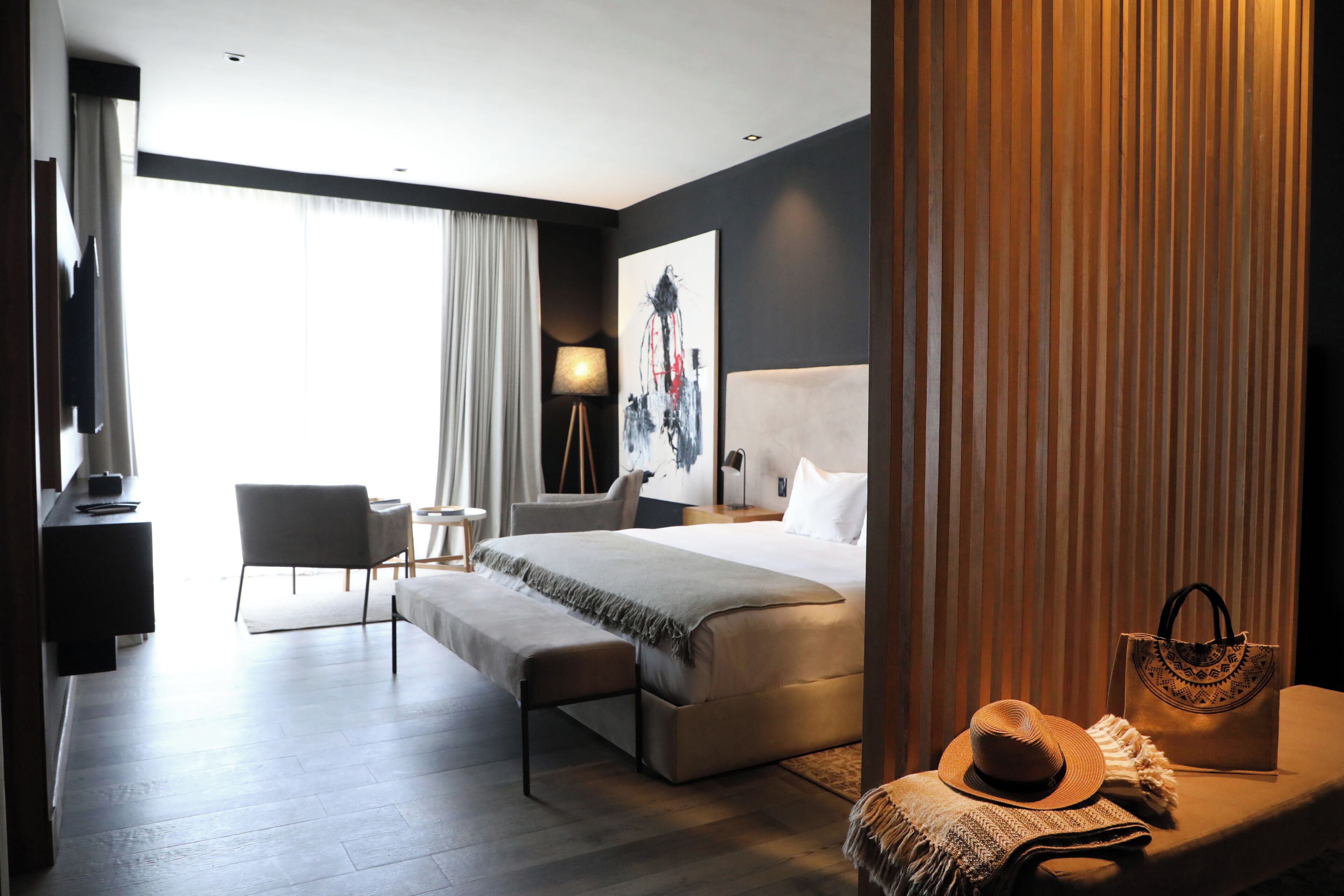Une chambre d’hôtel moderne, dotée d’un grand lit, d’un bureau, d’une chaise et offrant une vue sur l’extérieur.