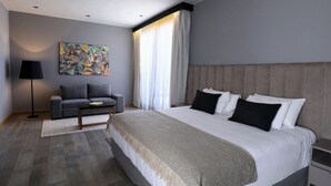 Et moderne hotelværelse med en stor seng, en sofa, et sofabord og et billede på væggen.