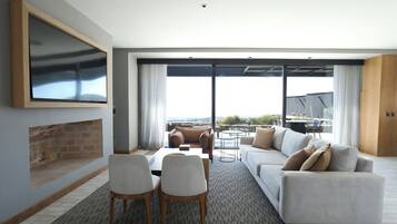 A modern living room with a fireplace, a sofa set, a dining area, and a large sliding glass door leading to an outdoor patio.