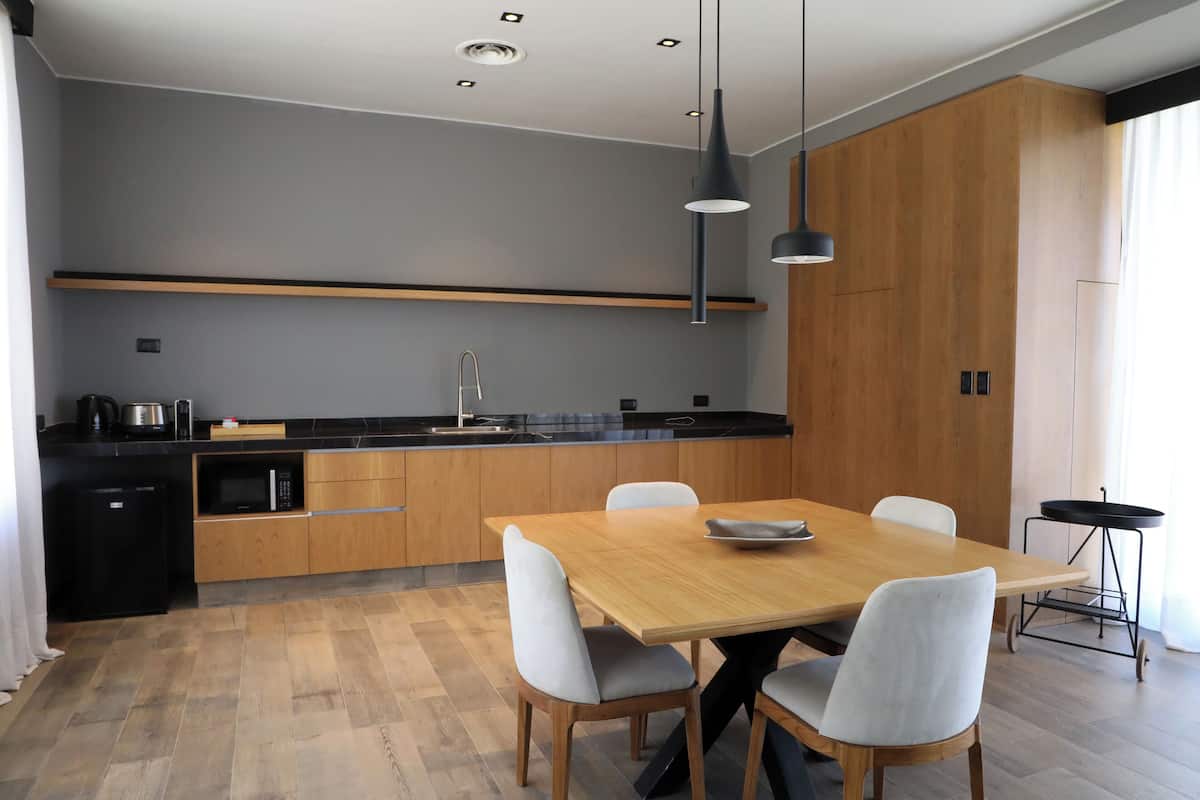 A modern kitchen with wooden cabinets, a black countertop, and a dining area with a wooden table and chairs.