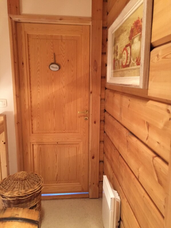 Una puerta de madera con una placa, una cesta de mimbre y un radiador.