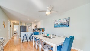 A modern kitchen with white cabinets, a central island, and blue bar stools. - Steps to Ocean: Water-View Carolina Beach Unit! (Carolina Beach)