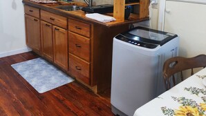 Una cocina compacta con armarios de madera, un lavaplatos empotrado, cafetera y lavavajillas.