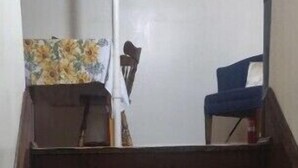 Un conjunto de escaleras de madera que conducen a una zona de descanso con una silla y una mesa cubierta con un mantel floral.