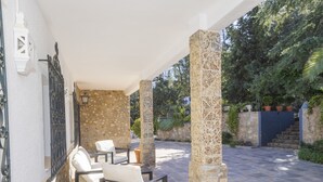 Un espace extérieur abrité, doté de piliers en pierre, d’un mur en pierre et offrant une vue sur un jardin.