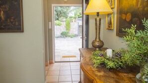 Un couloir avec un banc en bois, une lampe et une porte donnant sur un espace extérieur.