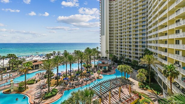 A resort with a large pool area, a beach, and a high-rise building.