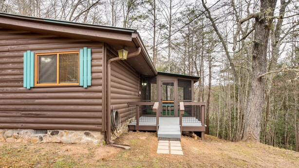 Una baita di legno con rivestimento in legno, un piccolo portico e fondamenta in pietra.