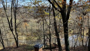 A wooden deck with a solar-powered device, surrounded by trees and a body of water.