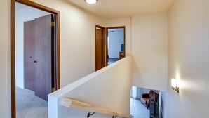 Una escalera con barandilla, una puerta de madera y un aplique en la pared.