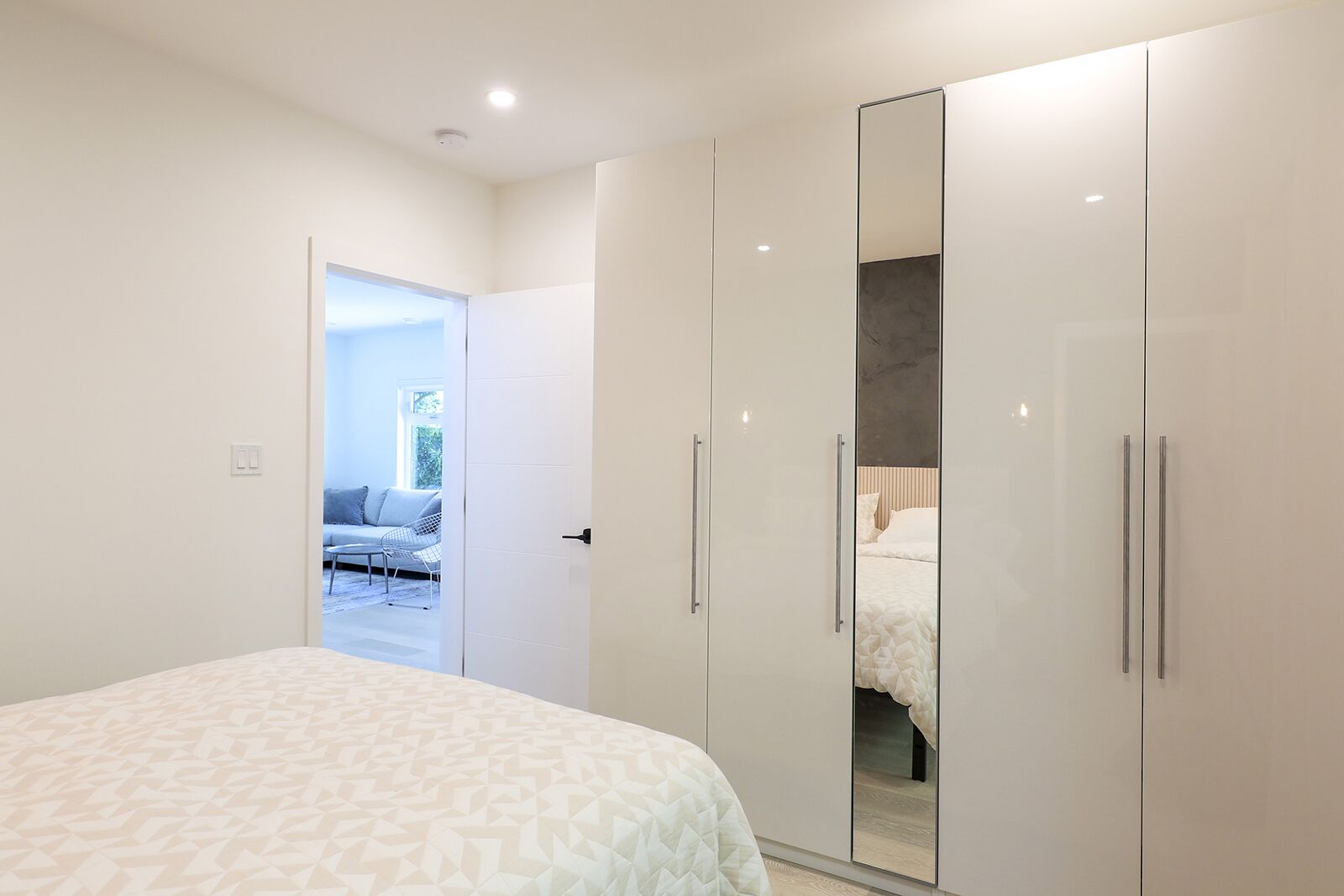 A bedroom with a large bed, a wardrobe, and a door leading to a balcony.