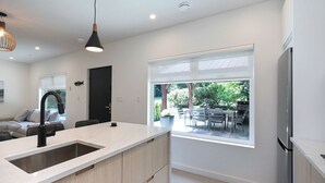 A modern kitchen with a large island, a built-in oven, and a dining area with outdoor seating. - Modern 2BR oceanfront apartment for sun, ski or mountain biking! (Courtenay)