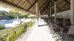 A covered outdoor area with a pool, lounge chairs, and tables.