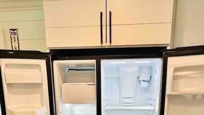 Ein offener Kühlschrank mit mehreren Ablagen und Schubladen, einem Gefrierfach und einem Wasserspender.