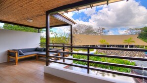 A modern room with a wooden ceiling, a wooden bench, and a view of a landscaped area with rocks and plants. - Casa Celeste lovely beach house (Jacó)