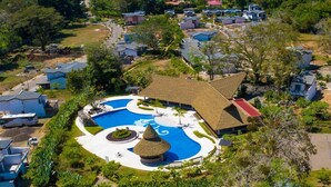 An aerial view of a resort with a central swimming pool, surrounded by villas and lush greenery. - Casa Celeste lovely beach house (Jacó)