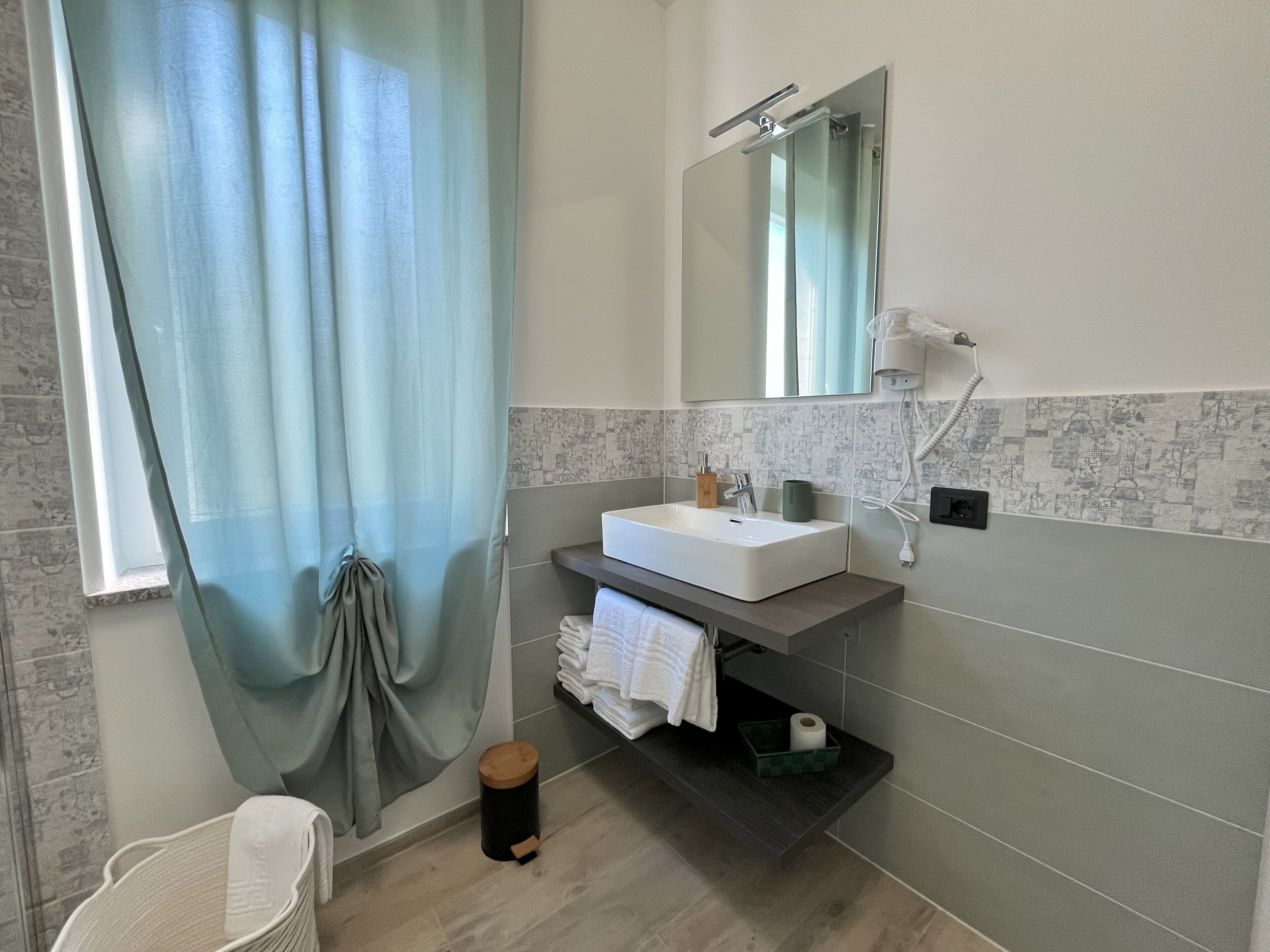 Une salle de bain moderne avec un grand miroir, un lavabo blanc et un porte-serviettes.