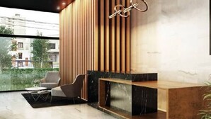 A modern reception area with a wooden slatted wall, a marble console table, and a seating area with a chair and a small table. - Syl's New Spacious Patio Pad (Miraflores)
