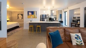 Un appartement moderne comprenant une cuisine, un espace de vie avec un canapé en cuir et une chambre à coucher avec un lit et une table de chevet.