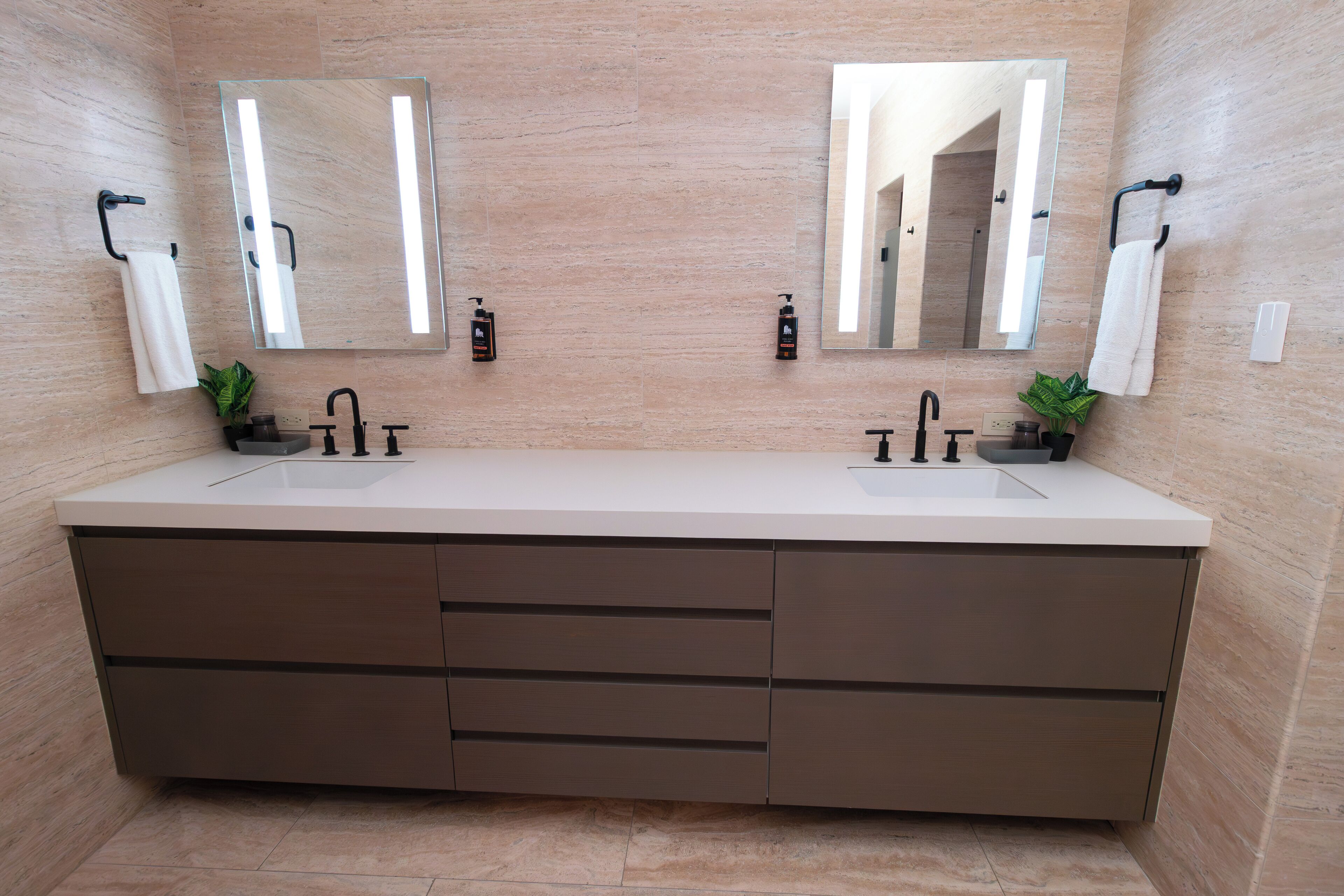 Une salle de bain moderne avec un meuble-lavabo à deux vasques, deux miroirs et deux plantes.