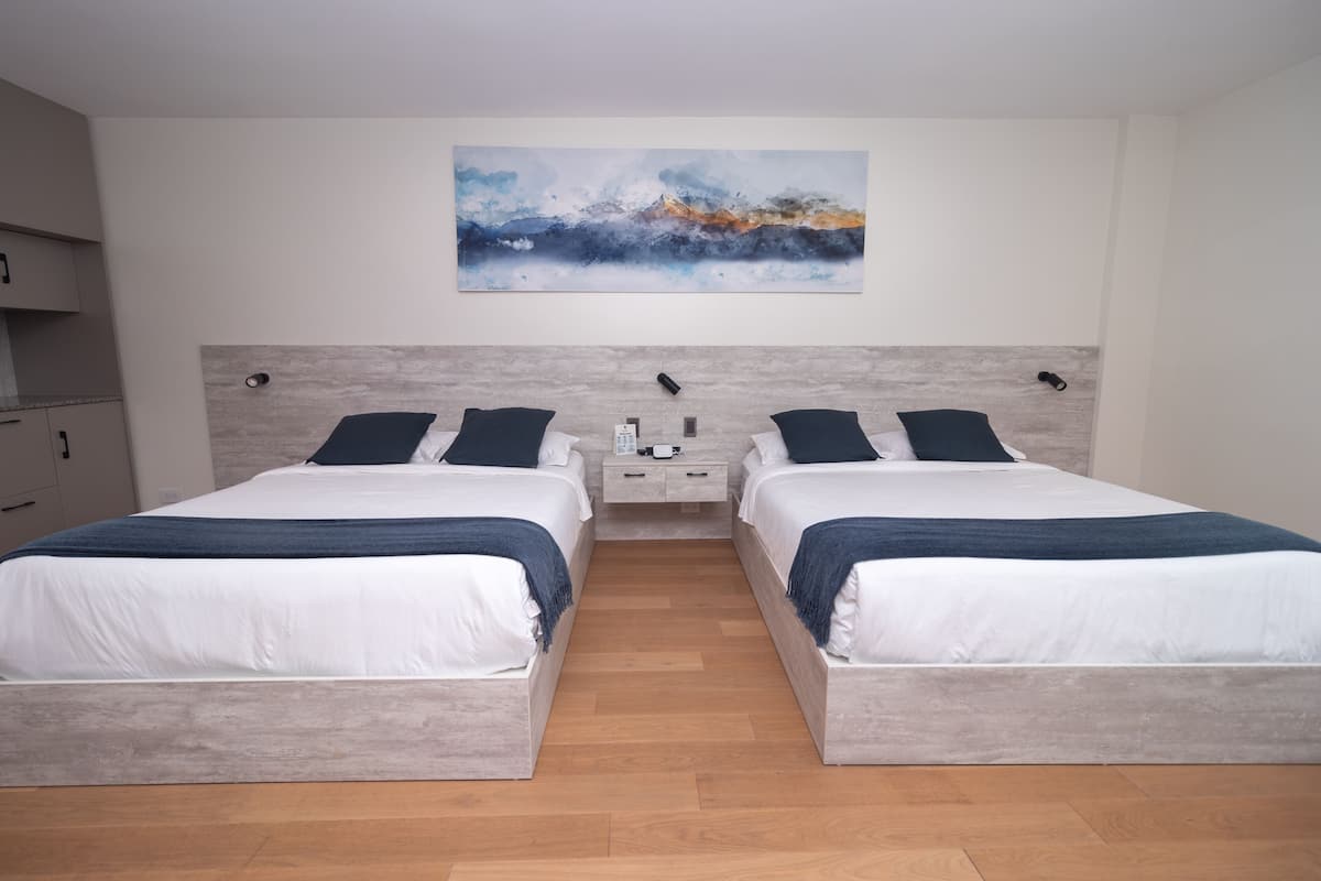 A modern hotel room with two beds, a nightstand, and a painting on the wall.