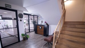 Een receptie met een houten trap, een receptiebalie en een klok aan de muur.